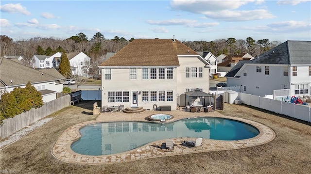 back of house with a fenced in pool, a patio, an in ground hot tub, a residential view, and a fenced backyard