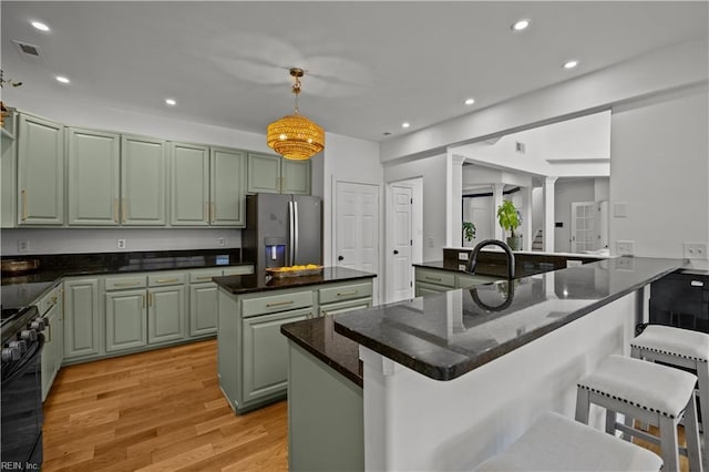 kitchen featuring stainless steel fridge with ice dispenser, recessed lighting, gas stove, a kitchen island, and a kitchen bar