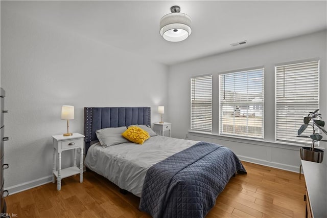 bedroom featuring visible vents, baseboards, and wood finished floors