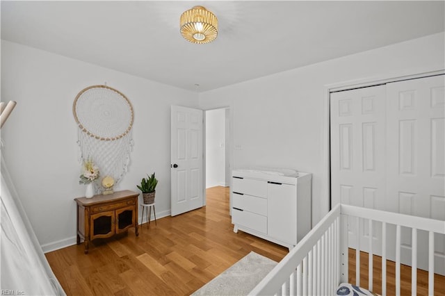 bedroom with light wood-style floors, baseboards, and a closet