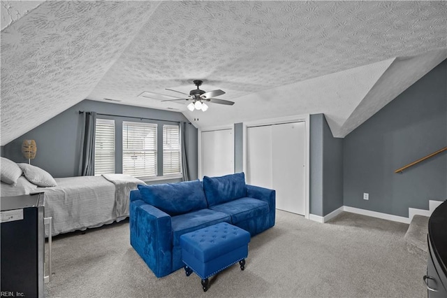 bedroom featuring baseboards, a ceiling fan, a textured ceiling, carpet floors, and multiple closets