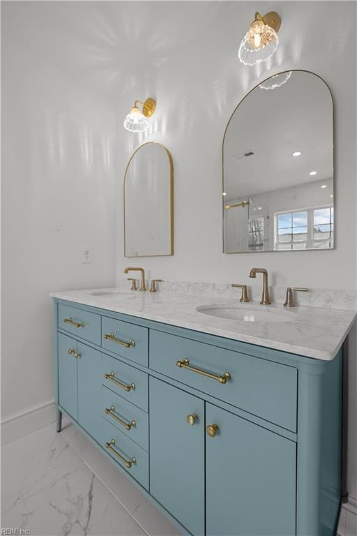 bathroom with double vanity, marble finish floor, baseboards, and a sink