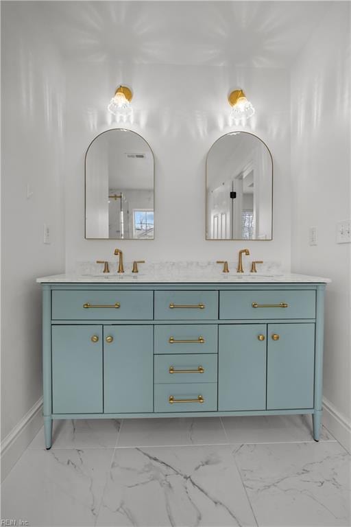 bathroom featuring marble finish floor, a sink, baseboards, and double vanity