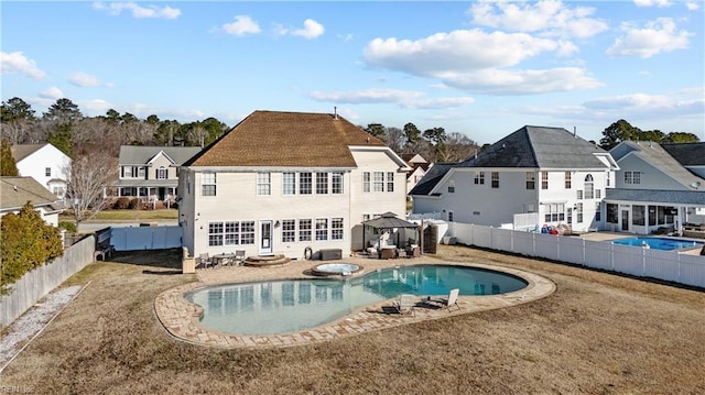 rear view of property featuring a fenced backyard, a residential view, a fenced in pool, and a gazebo