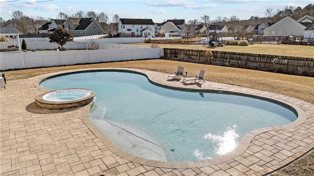 view of pool featuring a pool with connected hot tub, a residential view, a fenced backyard, and a patio