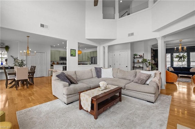 living area featuring a chandelier, visible vents, and ornate columns