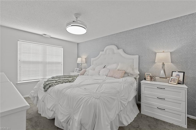 bedroom with baseboards, dark carpet, and a textured ceiling