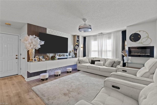 living area with wallpapered walls, wood finished floors, baseboards, and a textured ceiling