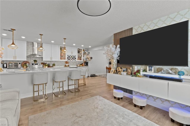 living area featuring baseboards, recessed lighting, a textured ceiling, and light wood-style floors