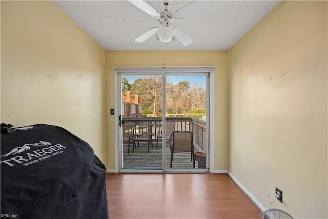 entryway with ceiling fan, a textured ceiling, baseboards, and wood finished floors