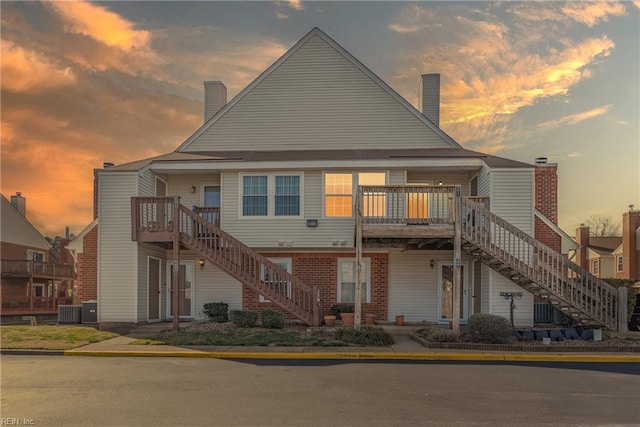 exterior space with brick siding, a chimney, a wooden deck, and stairs