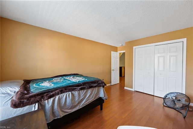 bedroom featuring a closet, a textured ceiling, baseboards, and wood finished floors