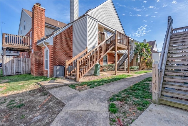 exterior space featuring central air condition unit, a chimney, stairway, and brick siding