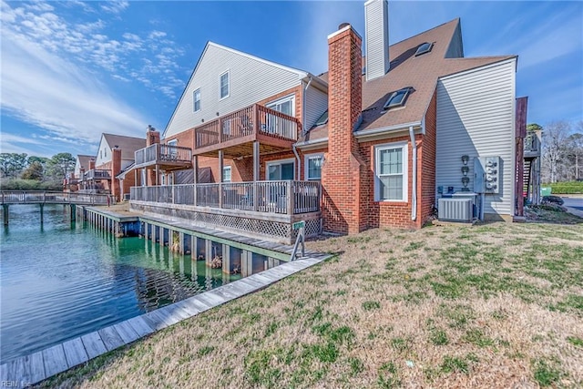 back of house with brick siding, a yard, a chimney, a water view, and cooling unit