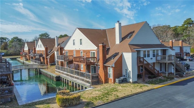 exterior space with central AC unit, a water view, stairs, a residential view, and a chimney