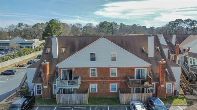 exterior space with uncovered parking, brick siding, a chimney, and fence