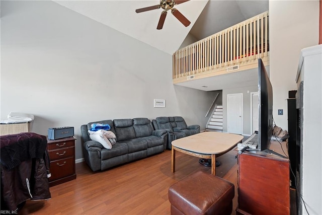 living room with stairs, ceiling fan, high vaulted ceiling, and wood finished floors