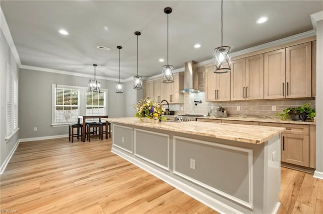kitchen featuring a spacious island, visible vents, ornamental molding, wall chimney range hood, and light wood-type flooring