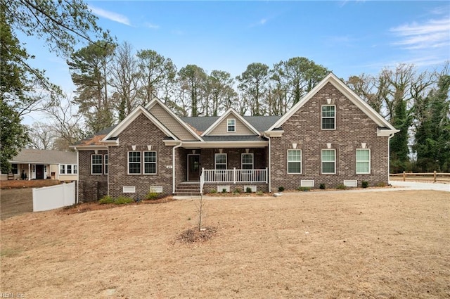 craftsman-style house featuring covered porch, brick siding, crawl space, and fence
