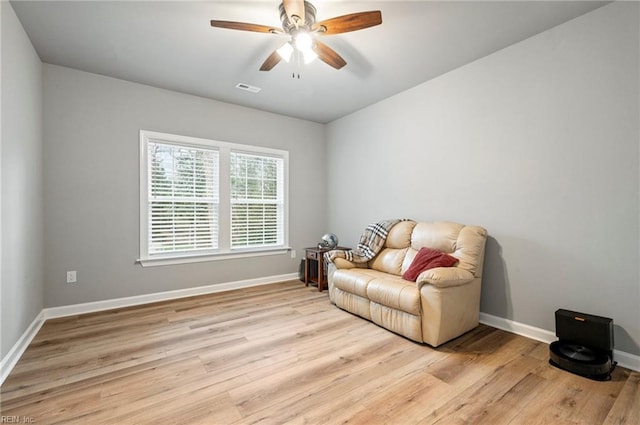 living area with light wood-style floors, visible vents, ceiling fan, and baseboards