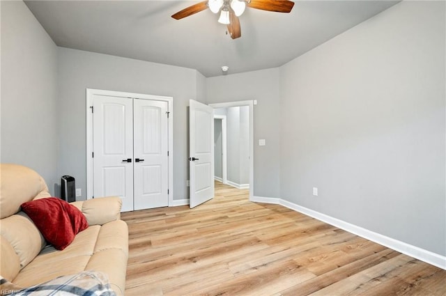 sitting room with a ceiling fan, light wood-type flooring, and baseboards