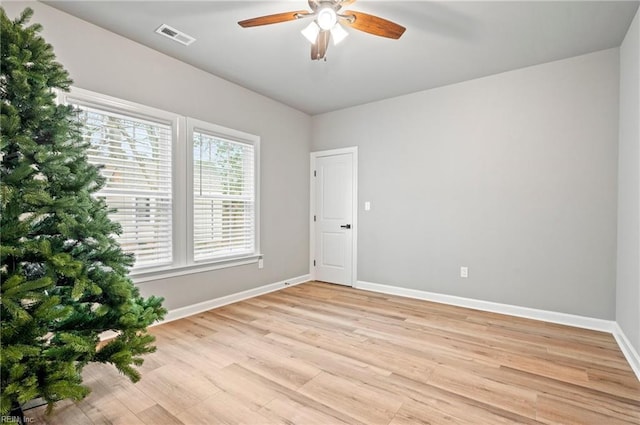 spare room featuring baseboards, a ceiling fan, visible vents, and light wood-style floors