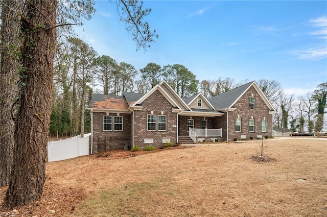 view of front of house featuring a porch, crawl space, brick siding, and fence