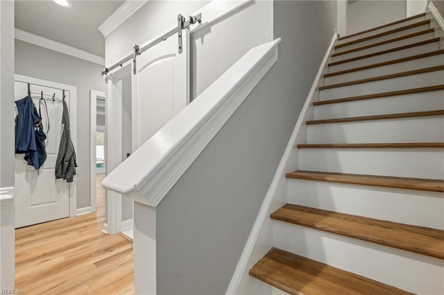 stairway featuring ornamental molding, wood finished floors, baseboards, and a barn door
