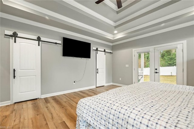 bedroom featuring a barn door, light wood-style floors, access to exterior, ornamental molding, and a raised ceiling