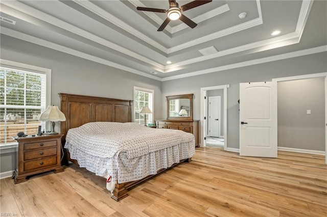 bedroom featuring light wood finished floors, baseboards, visible vents, a raised ceiling, and crown molding