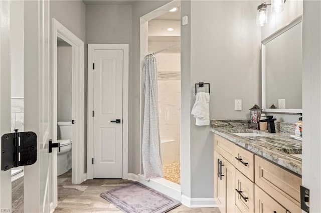 bathroom featuring toilet, a shower stall, vanity, and baseboards