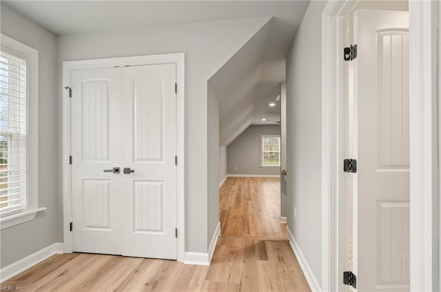 additional living space with baseboards, vaulted ceiling, and light wood-style floors