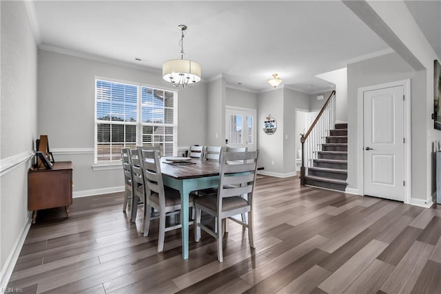 dining space featuring a chandelier, wood finished floors, baseboards, ornamental molding, and stairway