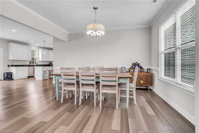 dining room with crown molding, a wealth of natural light, and light wood-style floors