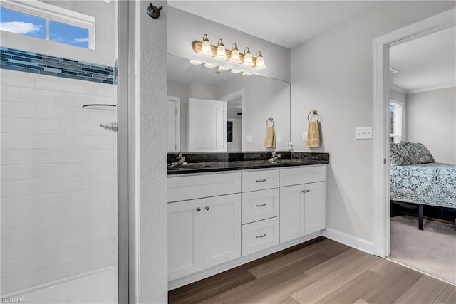 full bath featuring double vanity, a sink, ensuite bath, wood finished floors, and baseboards