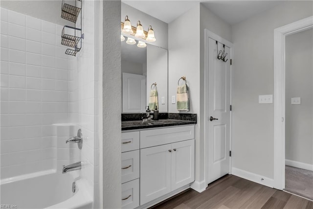 bathroom with bathing tub / shower combination, vanity, baseboards, and wood finished floors