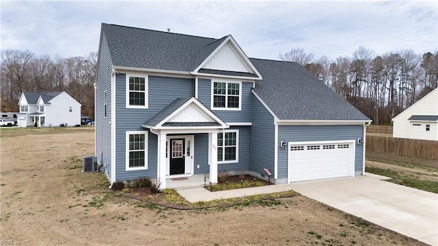 traditional home with a garage, concrete driveway, a shingled roof, and a front lawn