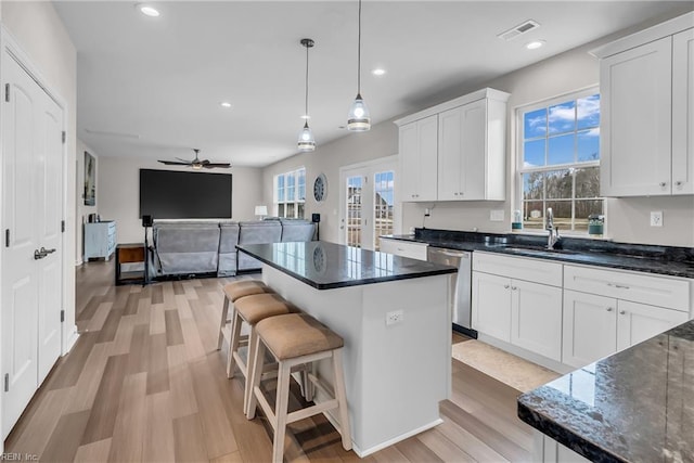 kitchen with stainless steel dishwasher, a sink, visible vents, and white cabinets