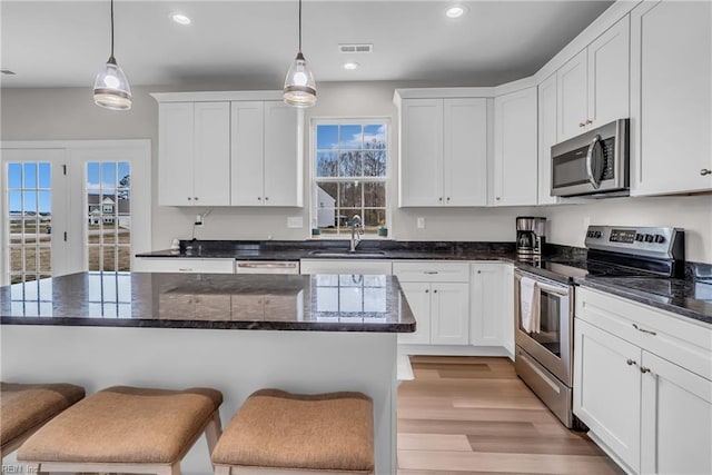 kitchen featuring light wood-style floors, white cabinetry, stainless steel appliances, and a sink