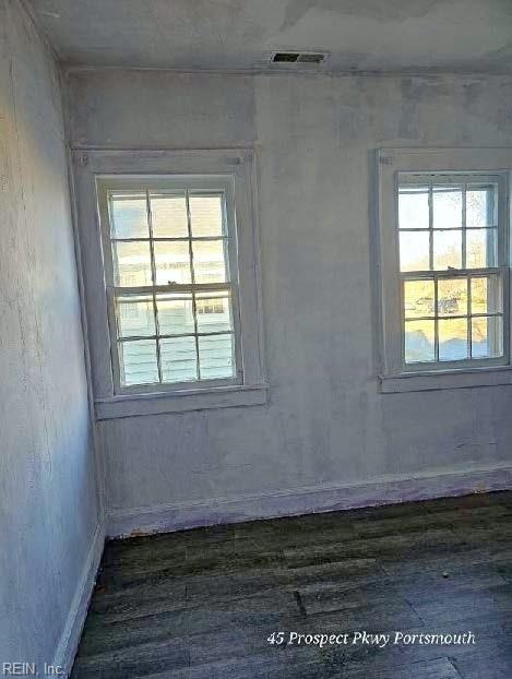 unfurnished room with dark wood-type flooring and visible vents