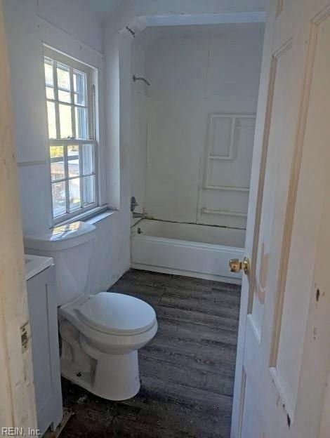 bathroom with toilet, tub / shower combination, vanity, wood finished floors, and washer / dryer