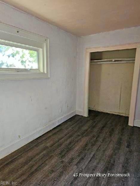 unfurnished bedroom with dark wood-style floors, a closet, and baseboards