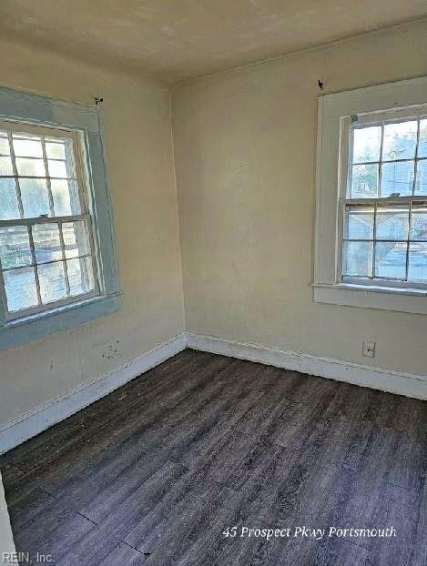 empty room featuring dark wood-style floors and baseboards