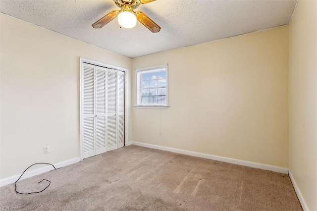 unfurnished bedroom featuring baseboards, ceiling fan, a textured ceiling, carpet floors, and a closet