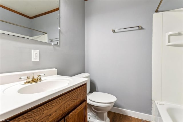 bathroom with baseboards, toilet, ornamental molding, wood finished floors, and vanity