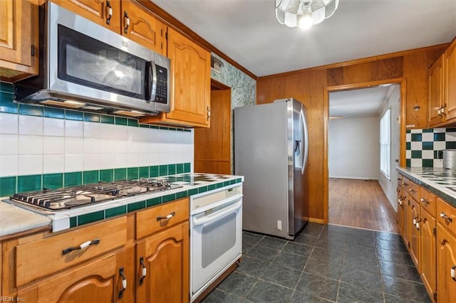 kitchen with tile countertops, brown cabinetry, stainless steel appliances, and crown molding