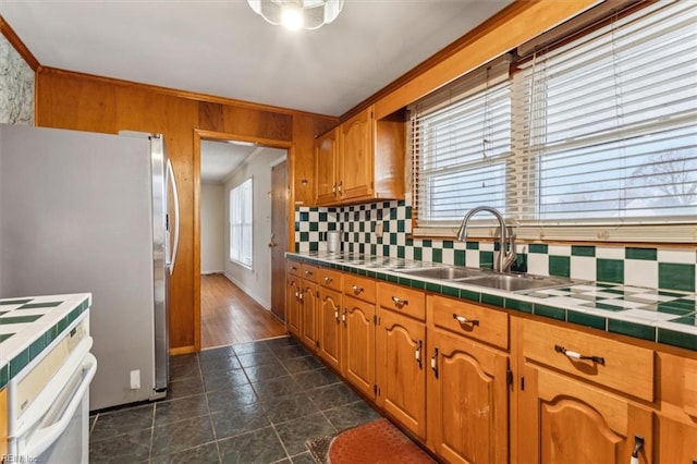 kitchen featuring tile countertops, a healthy amount of sunlight, stove, and a sink