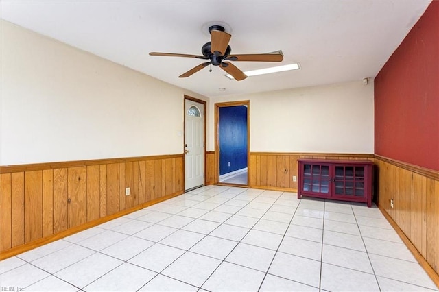 empty room featuring a wainscoted wall, ceiling fan, and wood walls