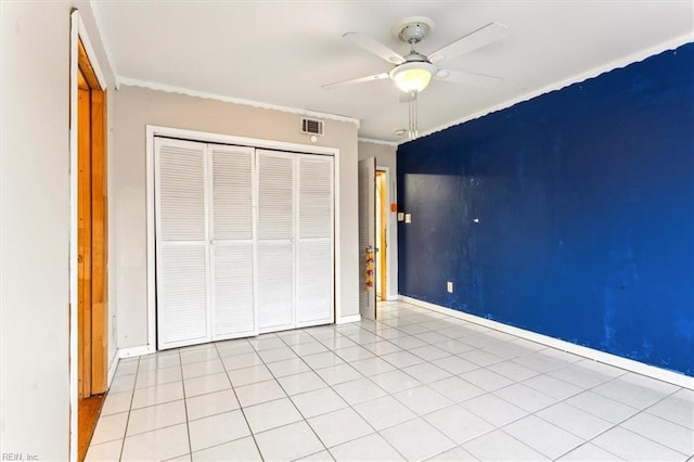 unfurnished bedroom with light tile patterned flooring, visible vents, baseboards, ornamental molding, and a closet