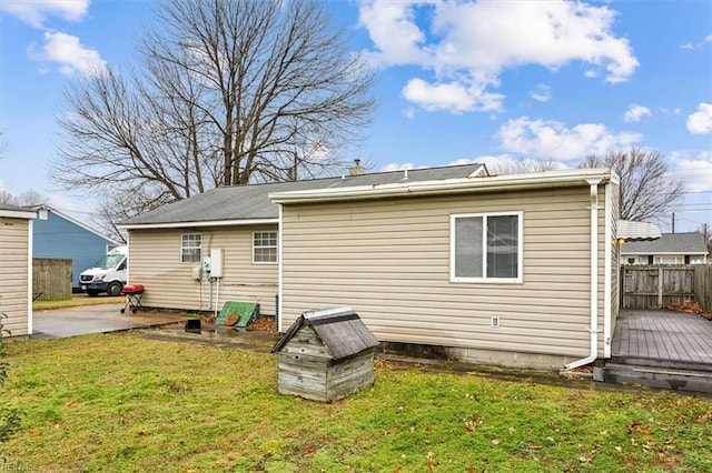 rear view of property featuring a yard, fence, and a wooden deck